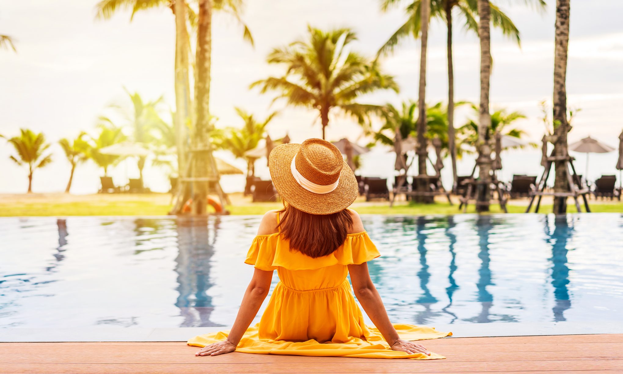 young-woman-traveler-relaxing-and-enjoying-the-sunset-by-a-tropical-resort-pool-while-traveling-for-summer-vacation